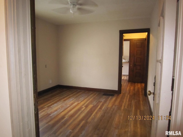 spare room with ceiling fan, baseboards, and dark wood-type flooring