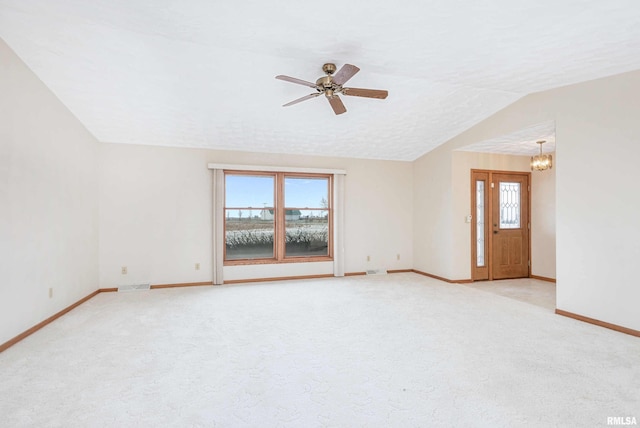 carpeted empty room featuring ceiling fan with notable chandelier, a textured ceiling, and vaulted ceiling