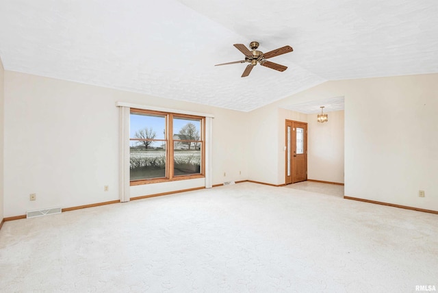 carpeted spare room with a textured ceiling, ceiling fan with notable chandelier, and vaulted ceiling