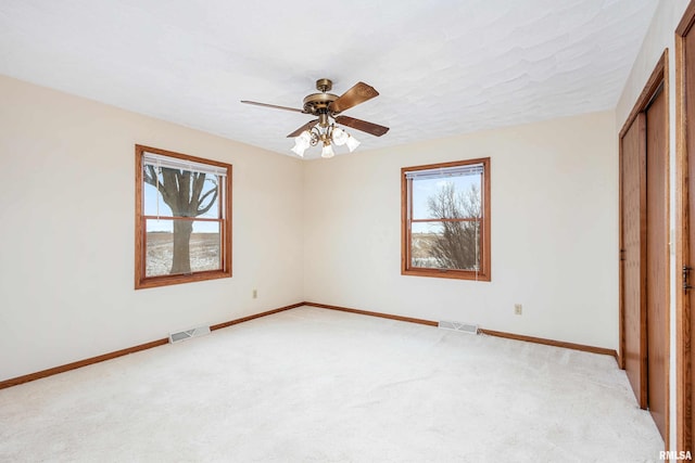 unfurnished bedroom with ceiling fan, a closet, light colored carpet, and multiple windows