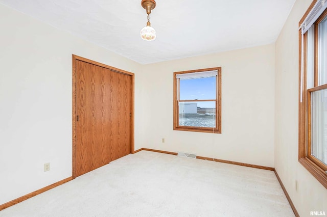 unfurnished bedroom featuring light carpet and a closet