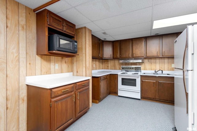 kitchen featuring a paneled ceiling, wood walls, sink, and white appliances