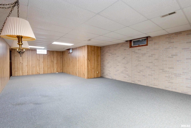 basement featuring wooden walls and a drop ceiling