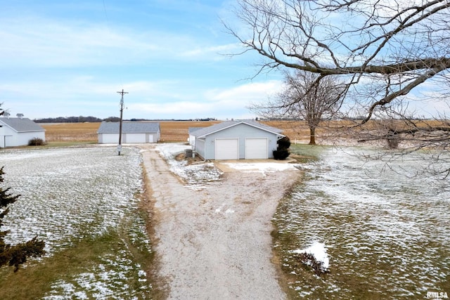 exterior space with a rural view, an outdoor structure, and a garage