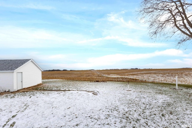 yard covered in snow featuring an outbuilding and a rural view