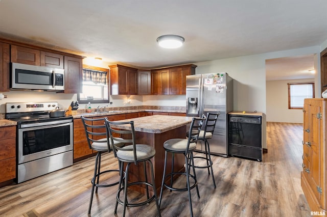 kitchen with a kitchen island, wood-type flooring, stainless steel appliances, and a breakfast bar area