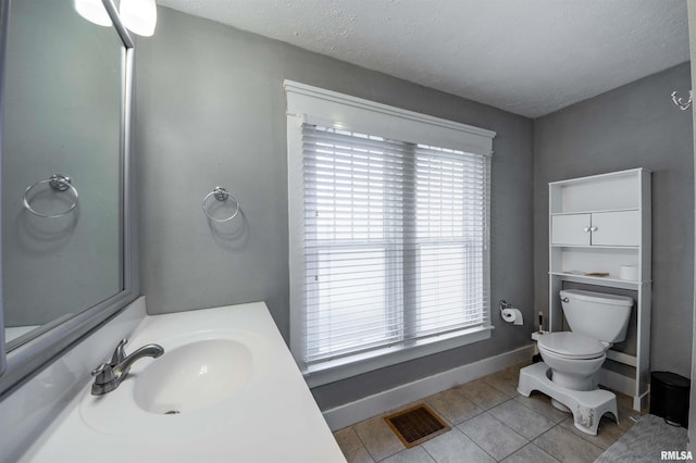 bathroom featuring tile patterned floors, sink, a textured ceiling, and toilet