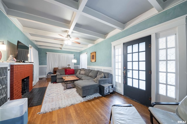 living room with beam ceiling, ceiling fan, coffered ceiling, hardwood / wood-style floors, and a fireplace