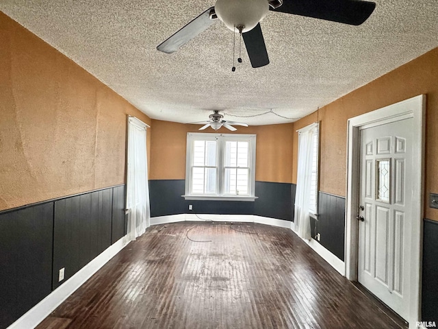 unfurnished dining area with a textured ceiling, dark hardwood / wood-style floors, and ceiling fan