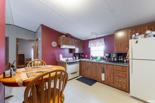 kitchen featuring a textured ceiling, white appliances, vaulted ceiling, and sink