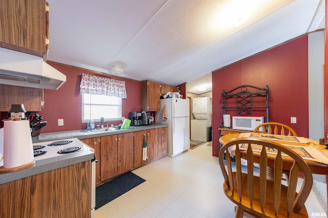 kitchen featuring white appliances, stacked washer and dryer, and lofted ceiling