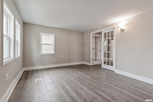 unfurnished room featuring hardwood / wood-style floors, a textured ceiling, and french doors