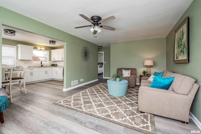 living room with ceiling fan, light hardwood / wood-style flooring, and sink