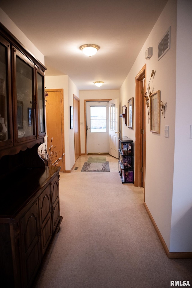 corridor with visible vents, light carpet, and baseboards