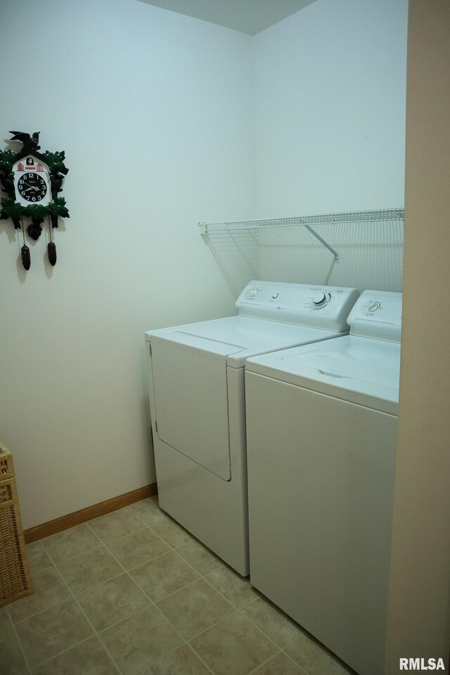 laundry room featuring laundry area, light tile patterned flooring, washer and clothes dryer, and baseboards