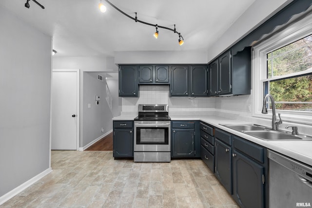 kitchen featuring sink, stainless steel appliances, backsplash, track lighting, and light wood-type flooring