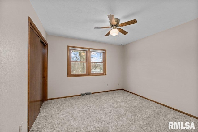 unfurnished bedroom featuring ceiling fan, a closet, and light carpet