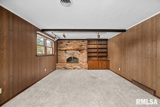 unfurnished living room featuring beamed ceiling, wood walls, crown molding, carpet floors, and a fireplace