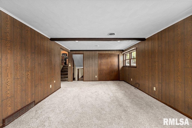 carpeted spare room with wooden walls, crown molding, beamed ceiling, and a textured ceiling