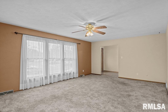 empty room with ceiling fan, light colored carpet, and a textured ceiling