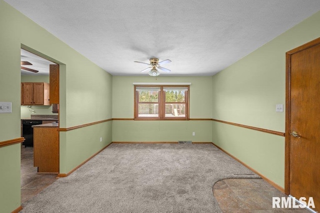 spare room with a textured ceiling, light colored carpet, and ceiling fan