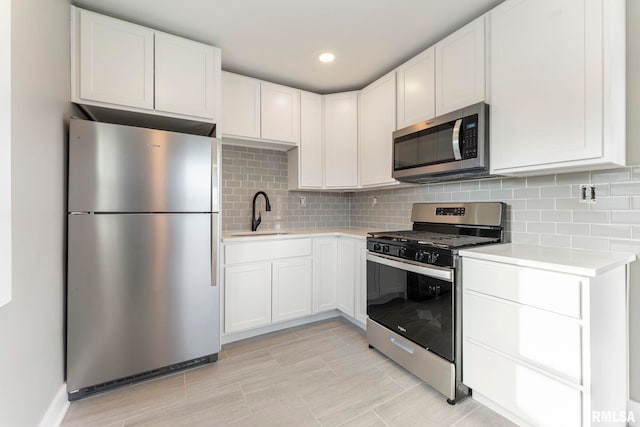 kitchen featuring decorative backsplash, sink, white cabinetry, and stainless steel appliances