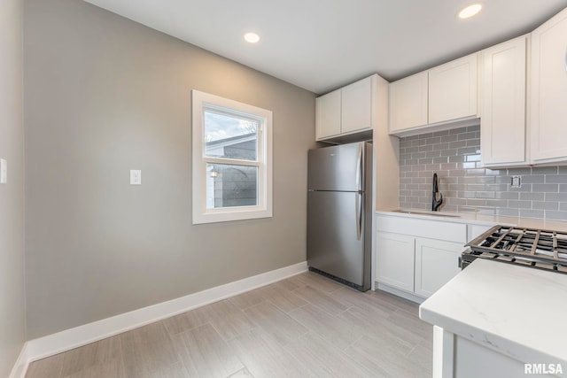 kitchen featuring backsplash, white cabinetry, sink, and appliances with stainless steel finishes