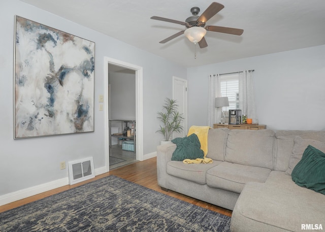 living room featuring ceiling fan and dark wood-type flooring