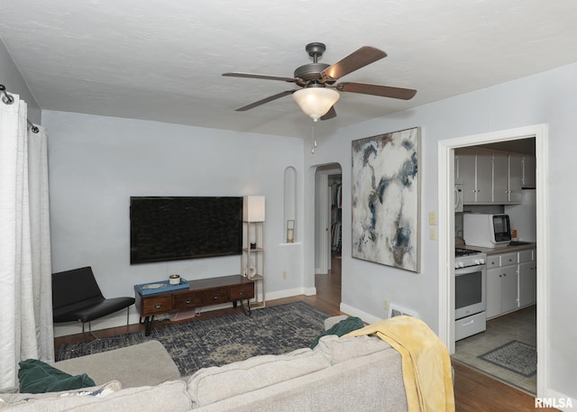 living room featuring ceiling fan and dark wood-type flooring