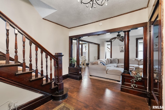 foyer featuring a textured ceiling, dark hardwood / wood-style floors, decorative columns, and ornamental molding