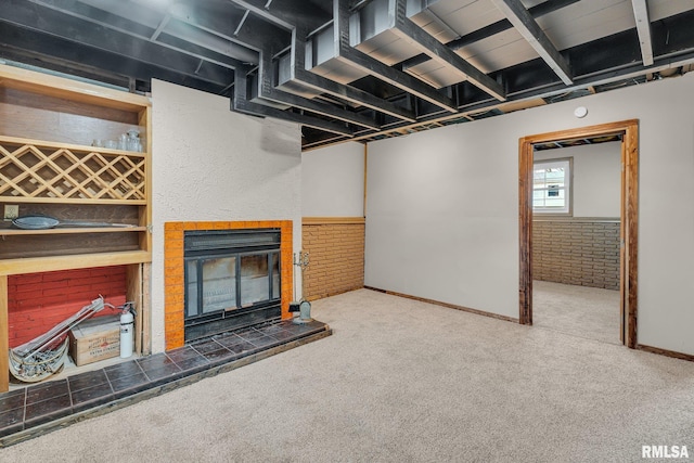 basement with carpet flooring, a fireplace, and brick wall