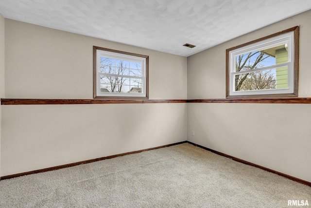 carpeted spare room featuring a textured ceiling and a healthy amount of sunlight