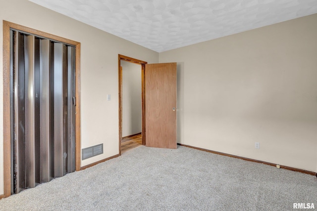 unfurnished bedroom with light colored carpet, a textured ceiling, and a closet