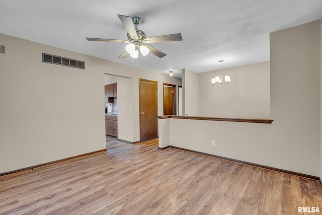 unfurnished living room featuring ceiling fan with notable chandelier and light hardwood / wood-style flooring