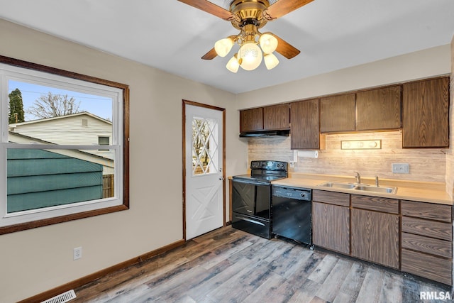 kitchen with a healthy amount of sunlight, sink, black appliances, and light hardwood / wood-style floors