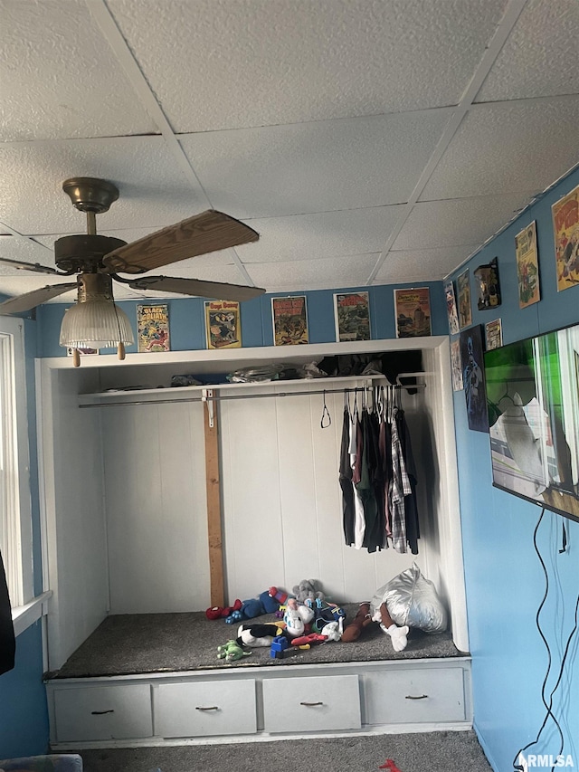 mudroom featuring ceiling fan, a drop ceiling, and carpet