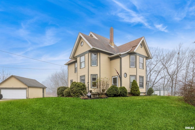 view of front of property featuring a garage, a front lawn, and an outdoor structure