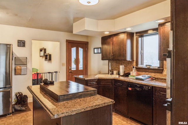 kitchen with a center island, sink, stainless steel fridge, black dishwasher, and tasteful backsplash