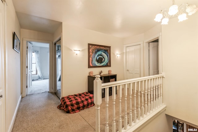 corridor with a notable chandelier and carpet floors