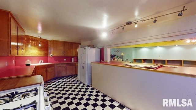 kitchen with rail lighting, white appliances, and sink