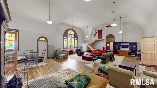 living room with ceiling fan, high vaulted ceiling, and wood-type flooring