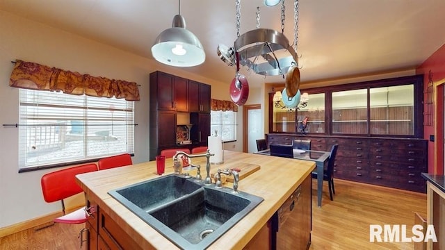 kitchen featuring hanging light fixtures, dishwasher, sink, and light hardwood / wood-style floors