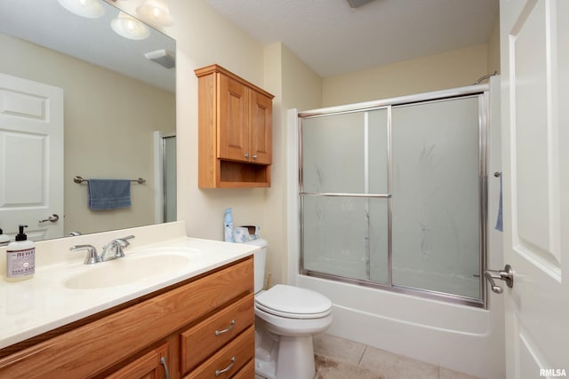 full bathroom with a textured ceiling, vanity, shower / bath combination with glass door, tile patterned flooring, and toilet