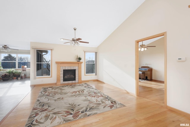 living room featuring ceiling fan, light hardwood / wood-style floors, high vaulted ceiling, and a brick fireplace