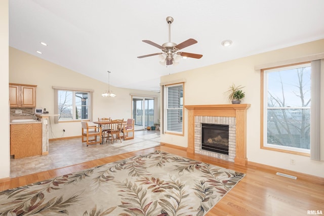 living room featuring a fireplace, light hardwood / wood-style flooring, ceiling fan, and lofted ceiling