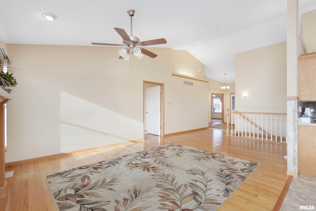 living room featuring ceiling fan with notable chandelier, light hardwood / wood-style floors, and high vaulted ceiling