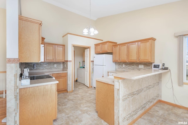 kitchen with pendant lighting, an inviting chandelier, white refrigerator, separate washer and dryer, and kitchen peninsula