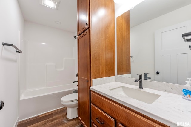 full bathroom with hardwood / wood-style floors, vanity,  shower combination, and toilet