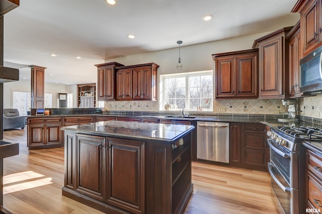 kitchen featuring plenty of natural light, a kitchen island, decorative light fixtures, and appliances with stainless steel finishes