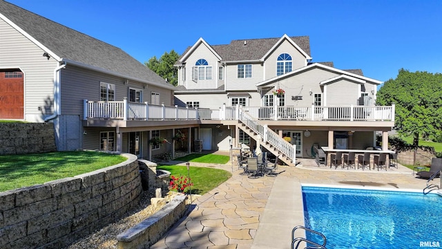 rear view of house featuring a lawn, a patio area, a swimming pool side deck, and a bar